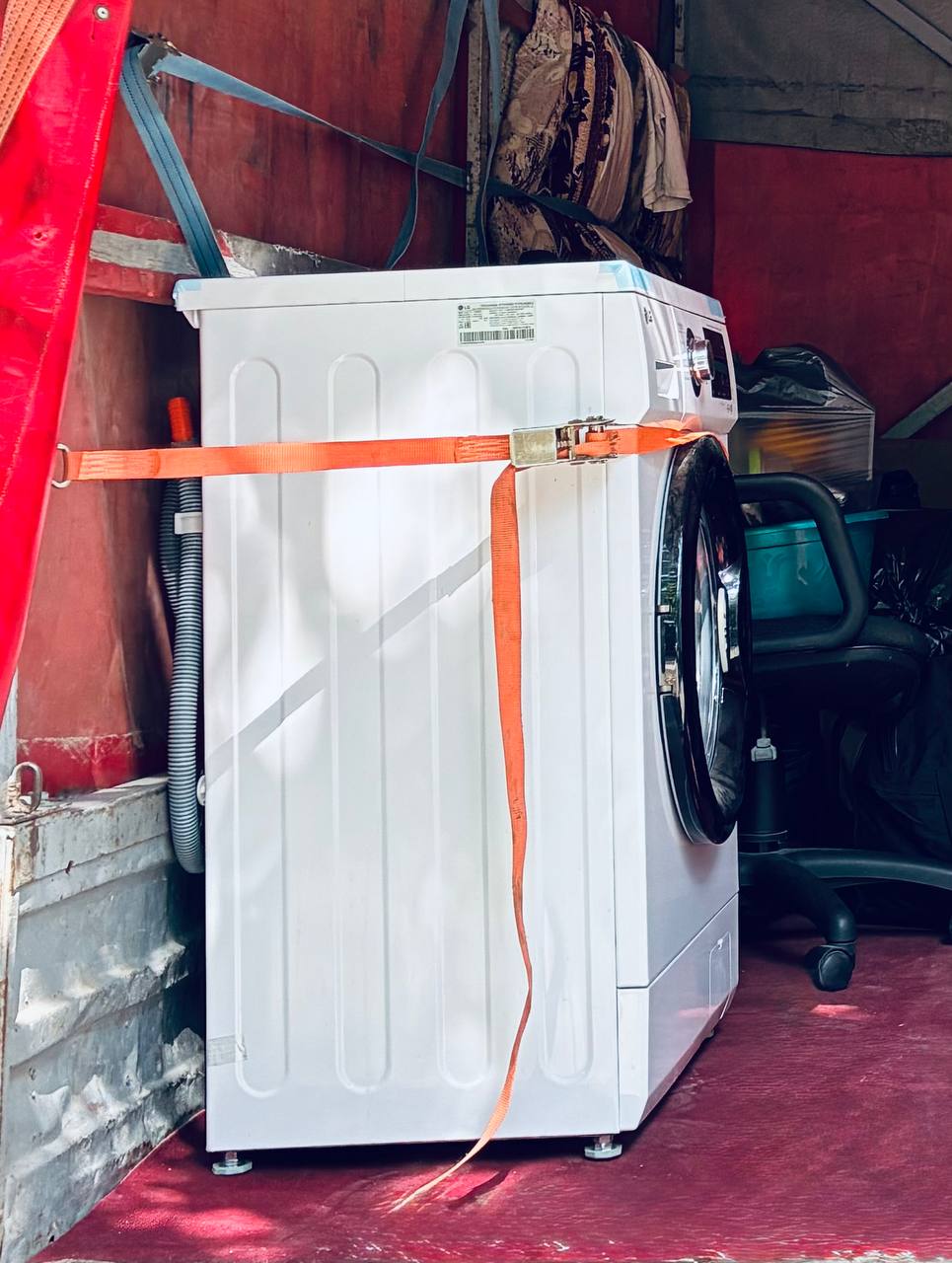 Стиральная машинка закреплена в грузовике для переезда, обеспечена страховочными ремнями